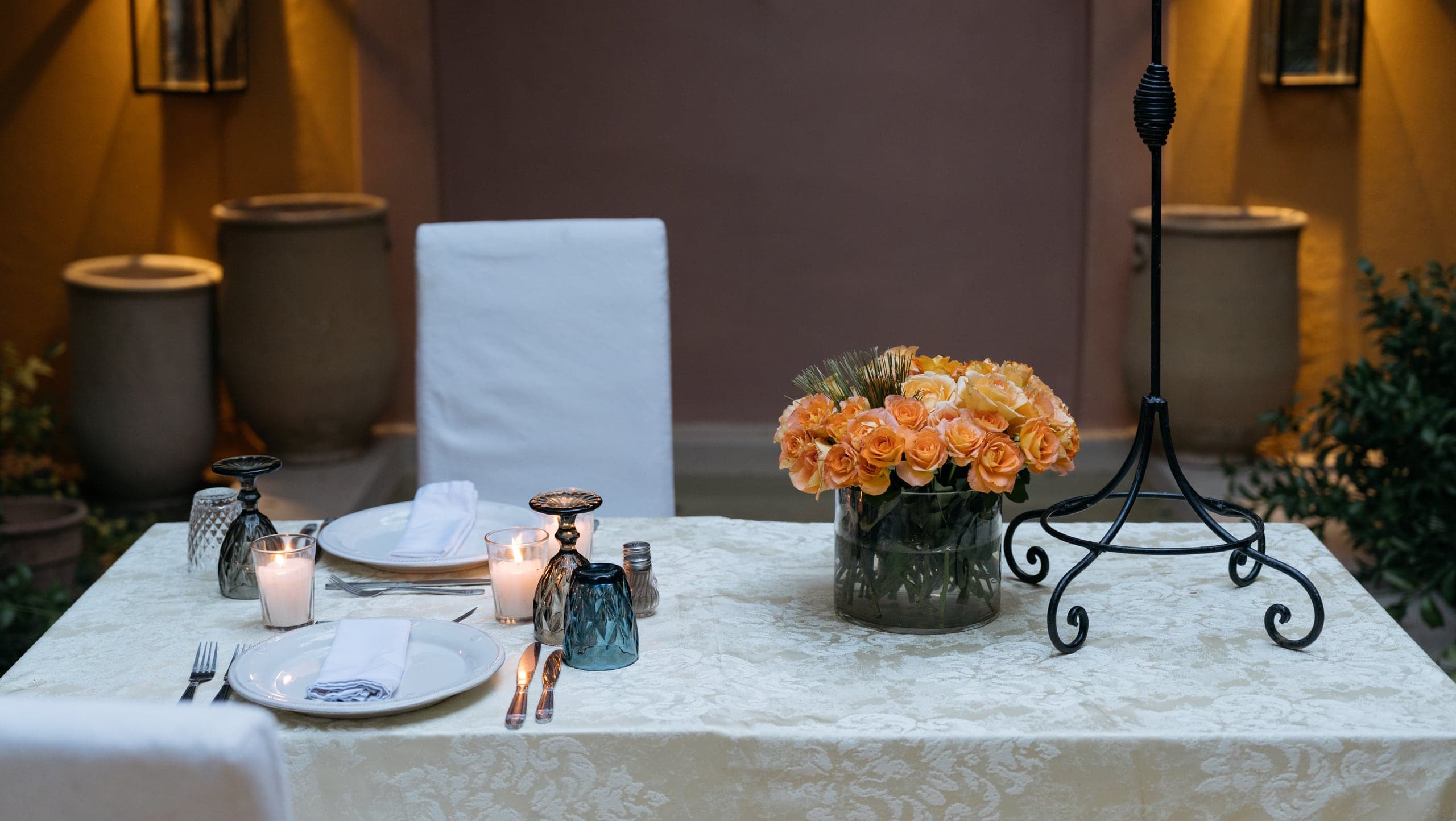 A table set for dinner with candles and orange roses