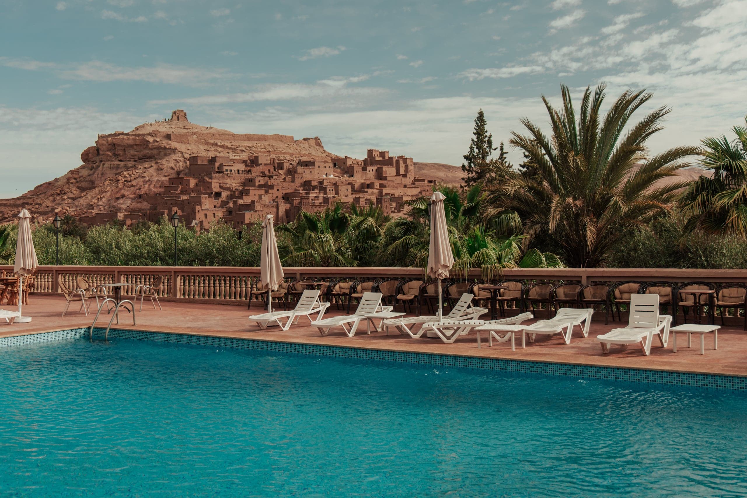 A hotel pool and loungers looking across to an earthen ksar