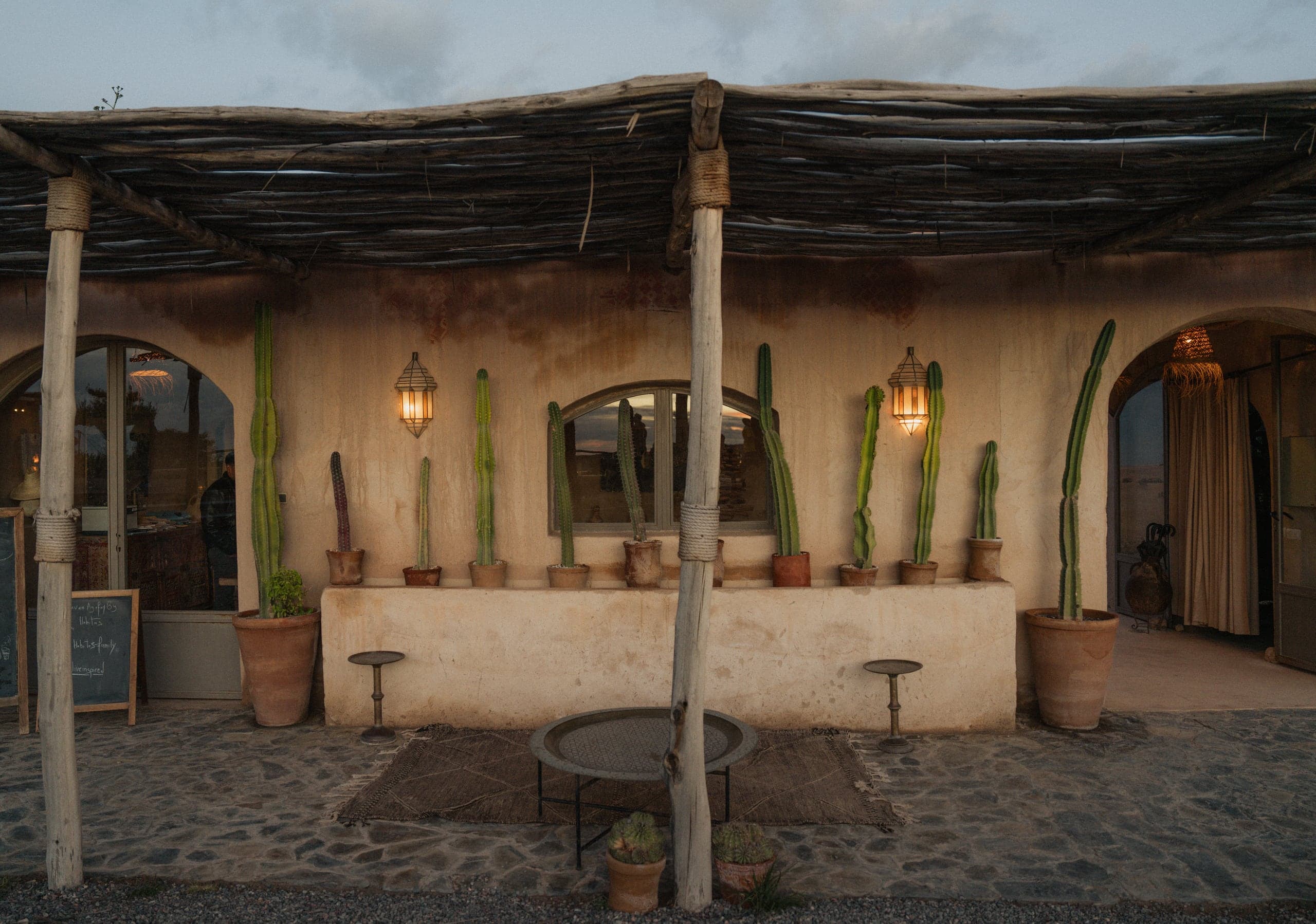 A shaded hotel terrace with cacti in clay pots and lanterns