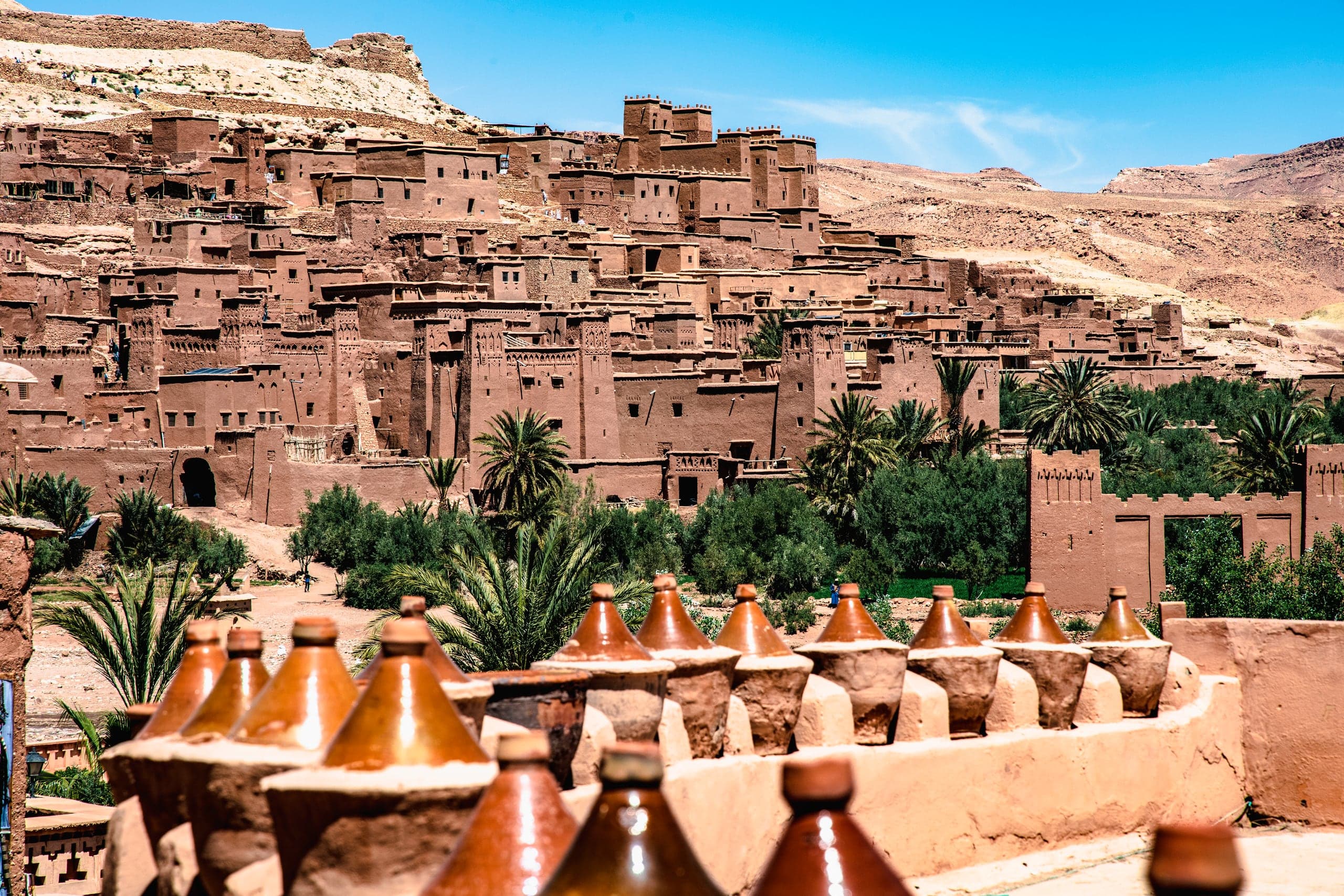Clay tagines lined up on a wall facing the ksar of Aït Benhaddou