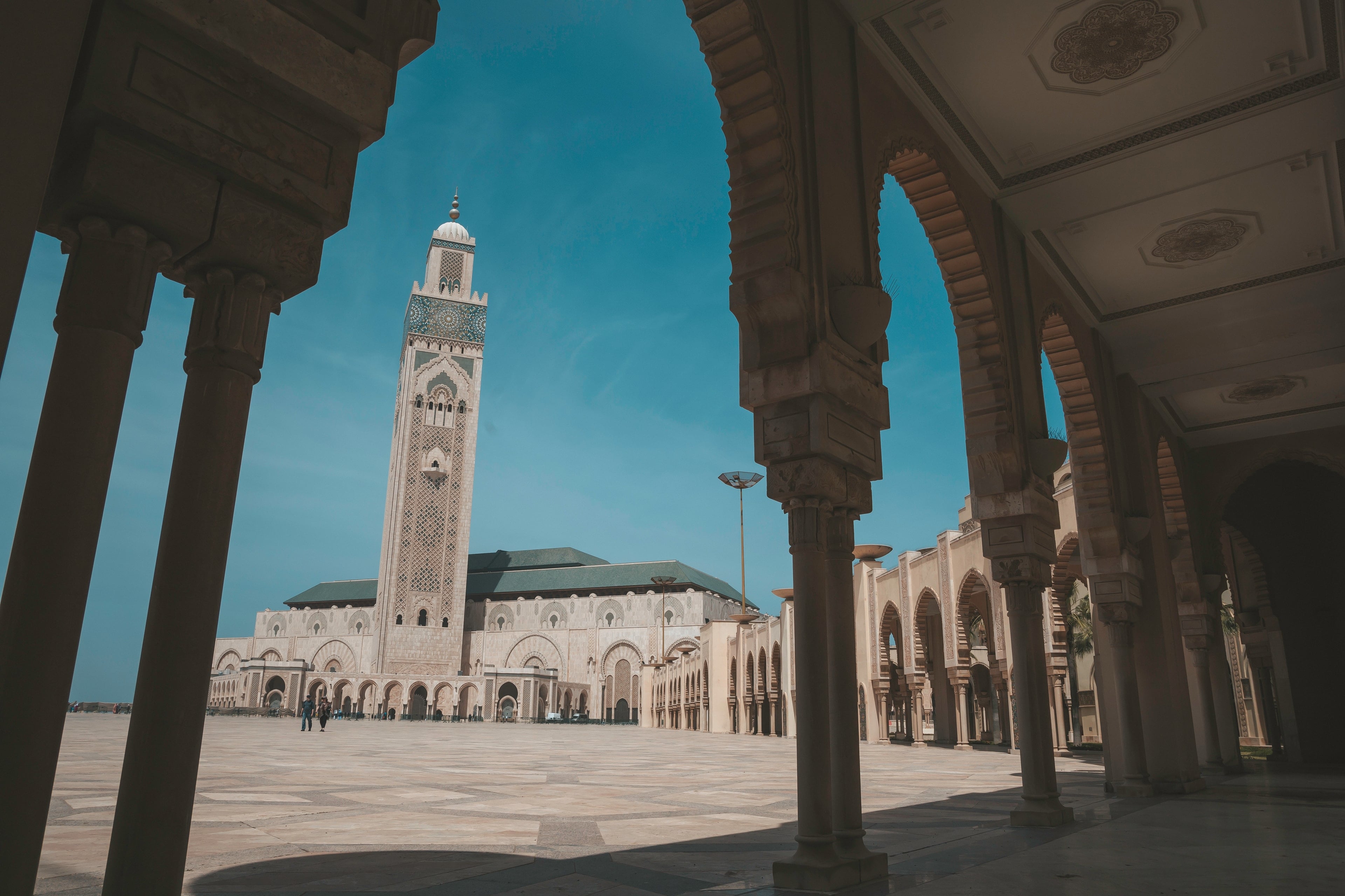 The minaret of the Hassan II Mosque framed by a shaded arcade