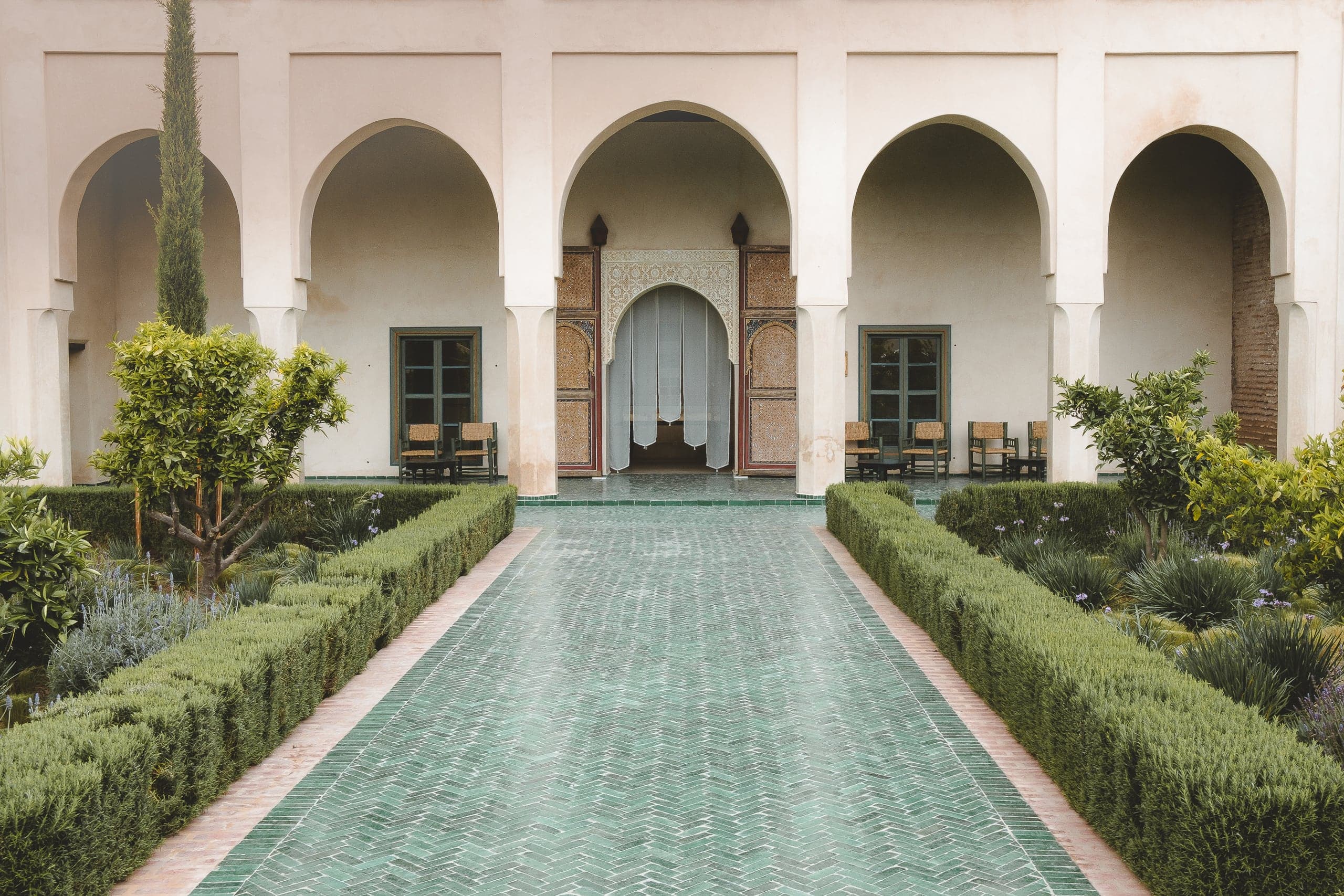 Arcades and a tiled path through the gardens of Le Jardin Secret