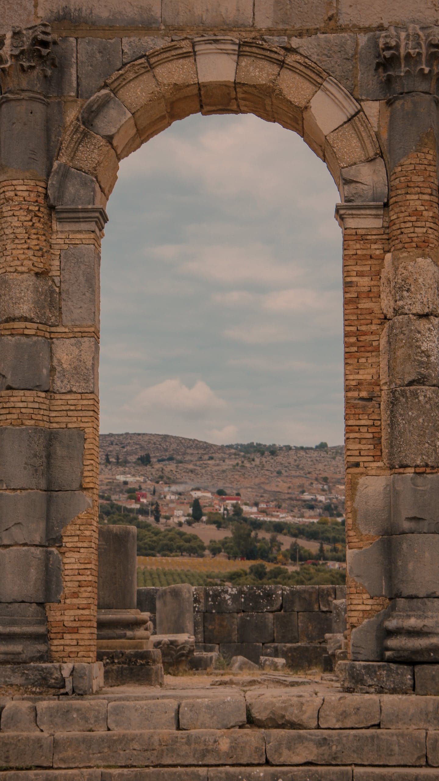 A stone Roman arch framing the hills beyond Volubilis
